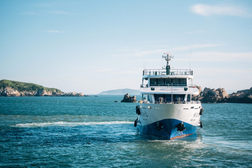 bateau de croisière blanc et bleu ancré près des côtes rocheuses de la méditerranée italienne