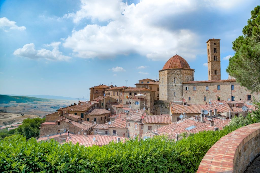 village médiéval toscan avec église à dôme rouge et campanile, paysage vallonné