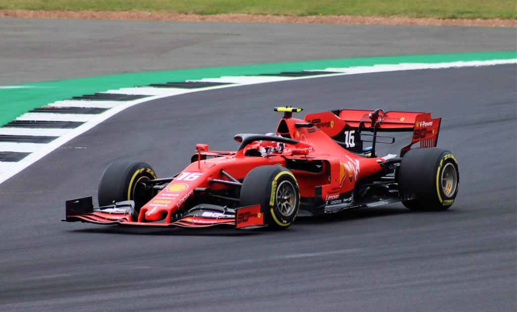 ferrari rouge numéro 16 sur circuit de f1 avec virage et ligne verte