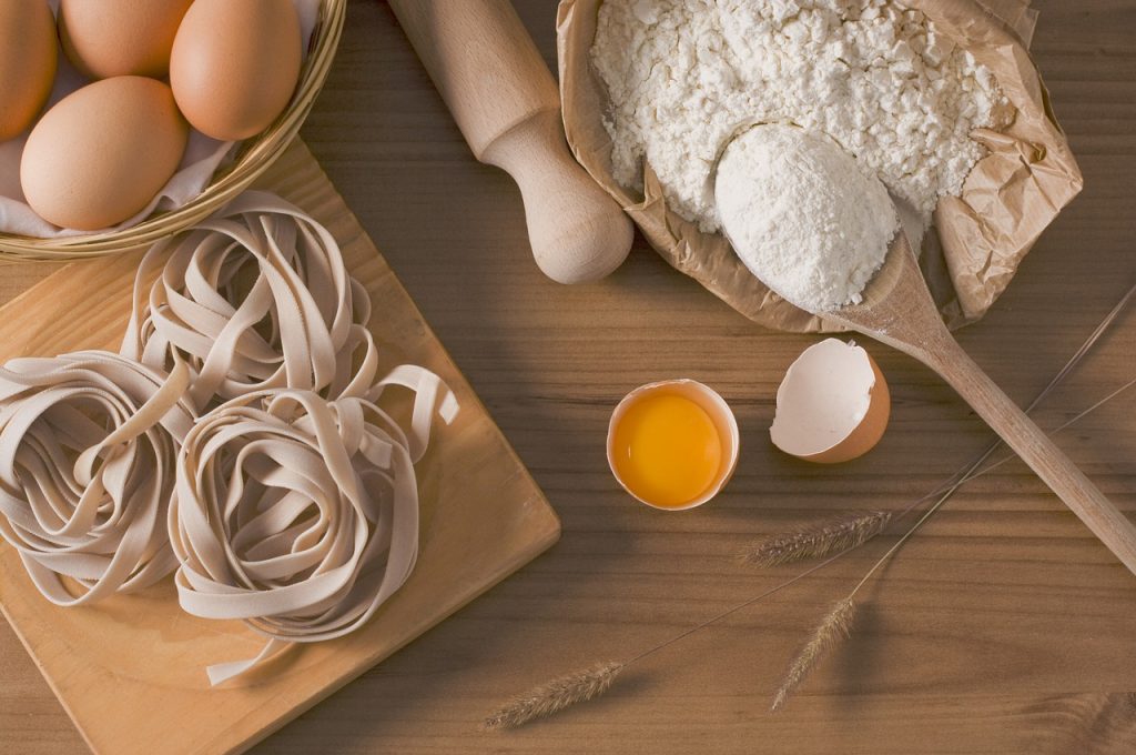 ingrédients de pâtes fraîches : œufs, farine et nouilles artisanales sur bois