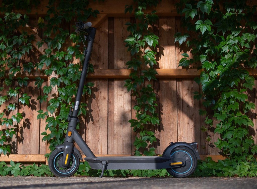 trottinette électrique noire Pony devant mur en bois avec lierre vert