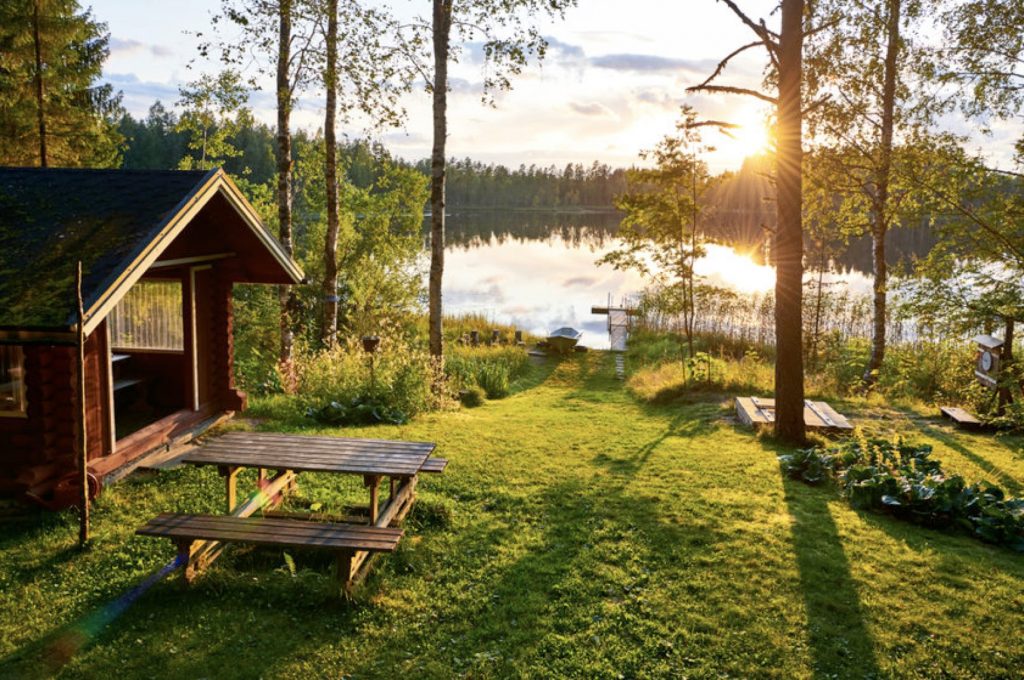 gîte en bois au bord d'un lac avec vue forestière au coucher de soleil