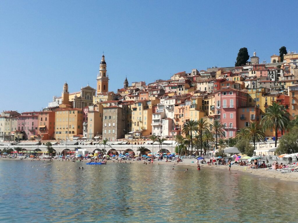 vue panoramique d'une ville côtière méditerranéenne avec plage, bâtiments colorés et église