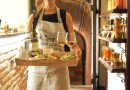 A waitress in a vintage apron serves wine and appetizers in a cozy, rustic indoor setting.