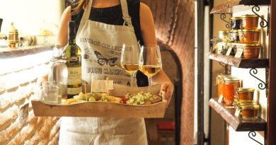 A waitress in a vintage apron serves wine and appetizers in a cozy, rustic indoor setting.