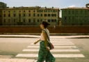 Casual stroll in historic Pisa, Tuscany with a side view of a woman crossing a sunlit street near old buildings.