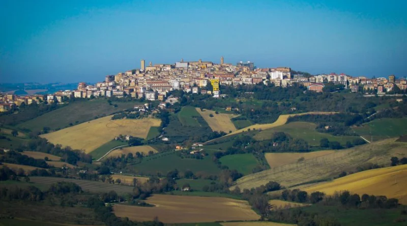A picturesque hilltop town in Italy surrounded by lush green fields and vibrant landscapes.
