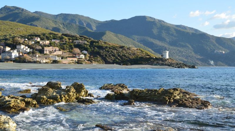 Beautiful coastal landscape in Ogliastro, Corse, France with rocky shoreline and distant mountains.