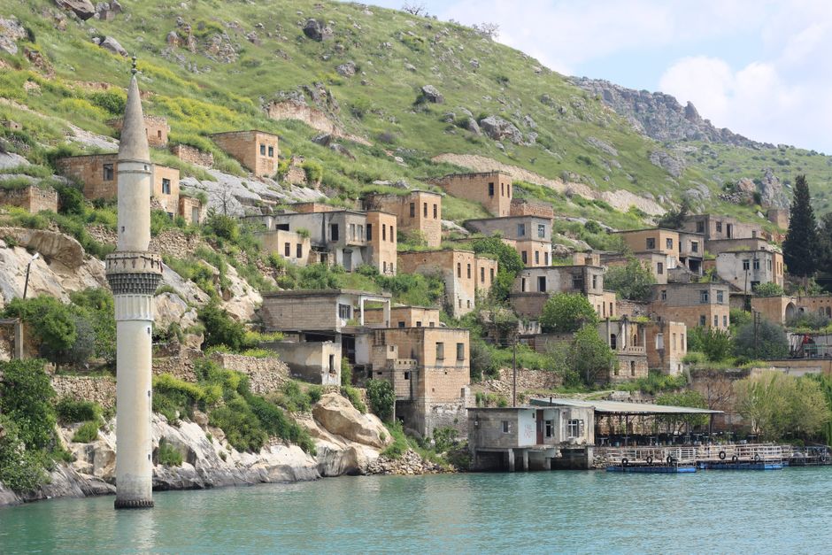 Picturesque Halfeti village with stone houses along the river, surrounded by lush hills.
