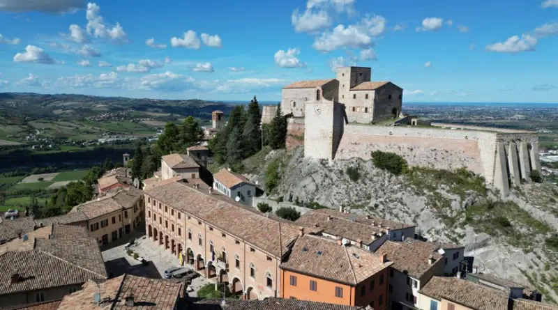 A stunning aerial view of the historic Verucchio Castle in Emilia-Romagna, Italy, against a clear sky.