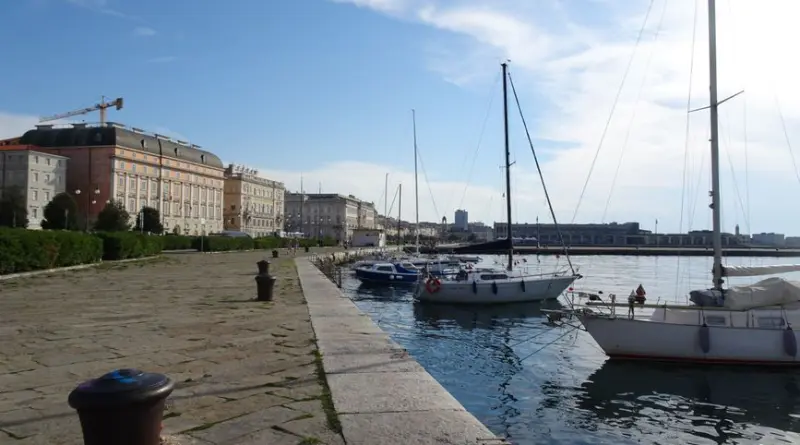 Explore the picturesque waterfront in Trieste, Italy with docked sailboats and historic architecture.