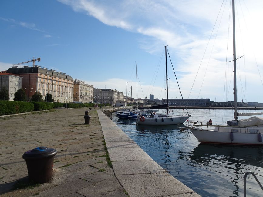 Explore the picturesque waterfront in Trieste, Italy with docked sailboats and historic architecture.