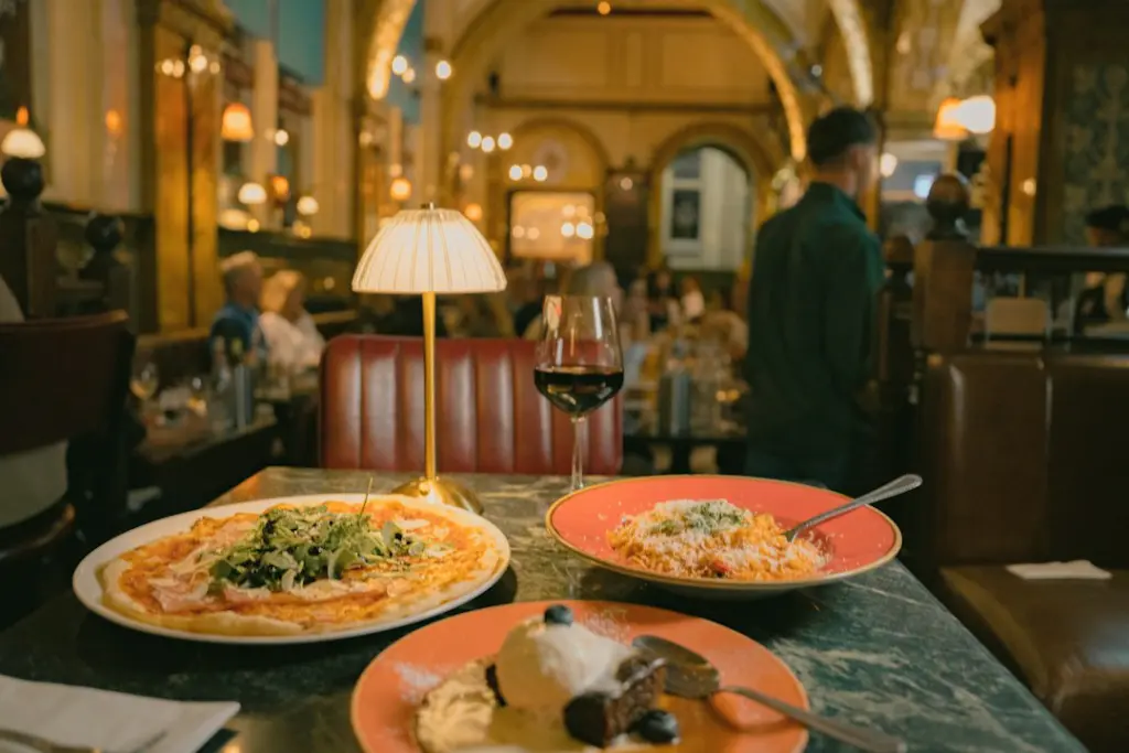 A pizza, pasta, and dessert on a marble table in a dimly lit restaurant