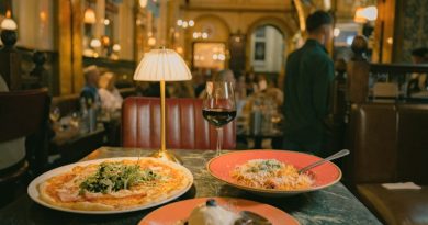 A pizza, pasta, and dessert on a marble table in a dimly lit restaurant