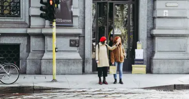 Two women stand by a streetlight in Milan, Italy, near a fashion store.