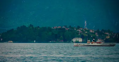 A vintage steamboat sails on a calm lake near shore