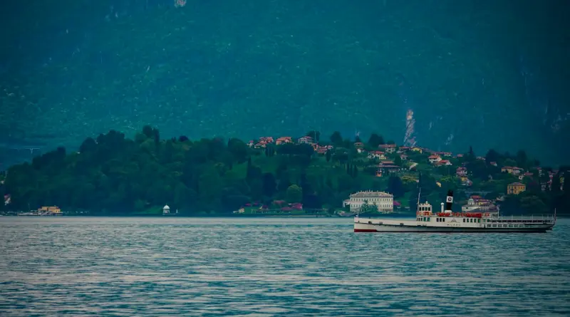 A vintage steamboat sails on a calm lake near shore